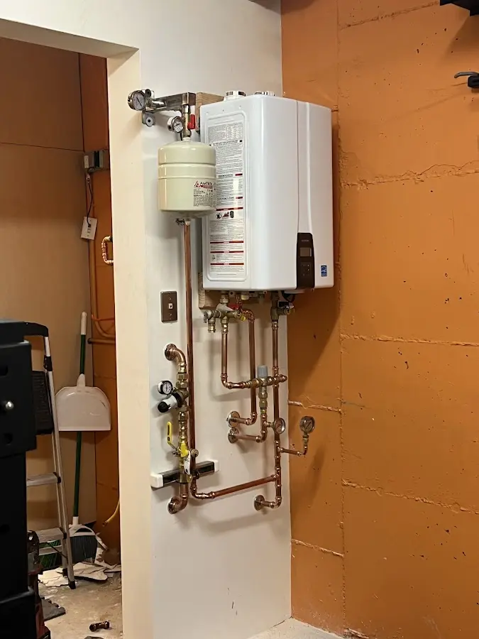 Plumbing technician inspecting water heater connections in Muttontown